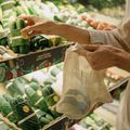 Filling a SuperBee mesh produce bag with vegetables at a market stall