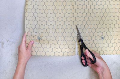 A honeycomb-print beeswax wrap roll being cut to size with scissors