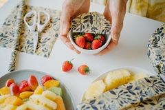 A bowl of strawberries covered with a SuperBee beeswax wrap beside cut fruit