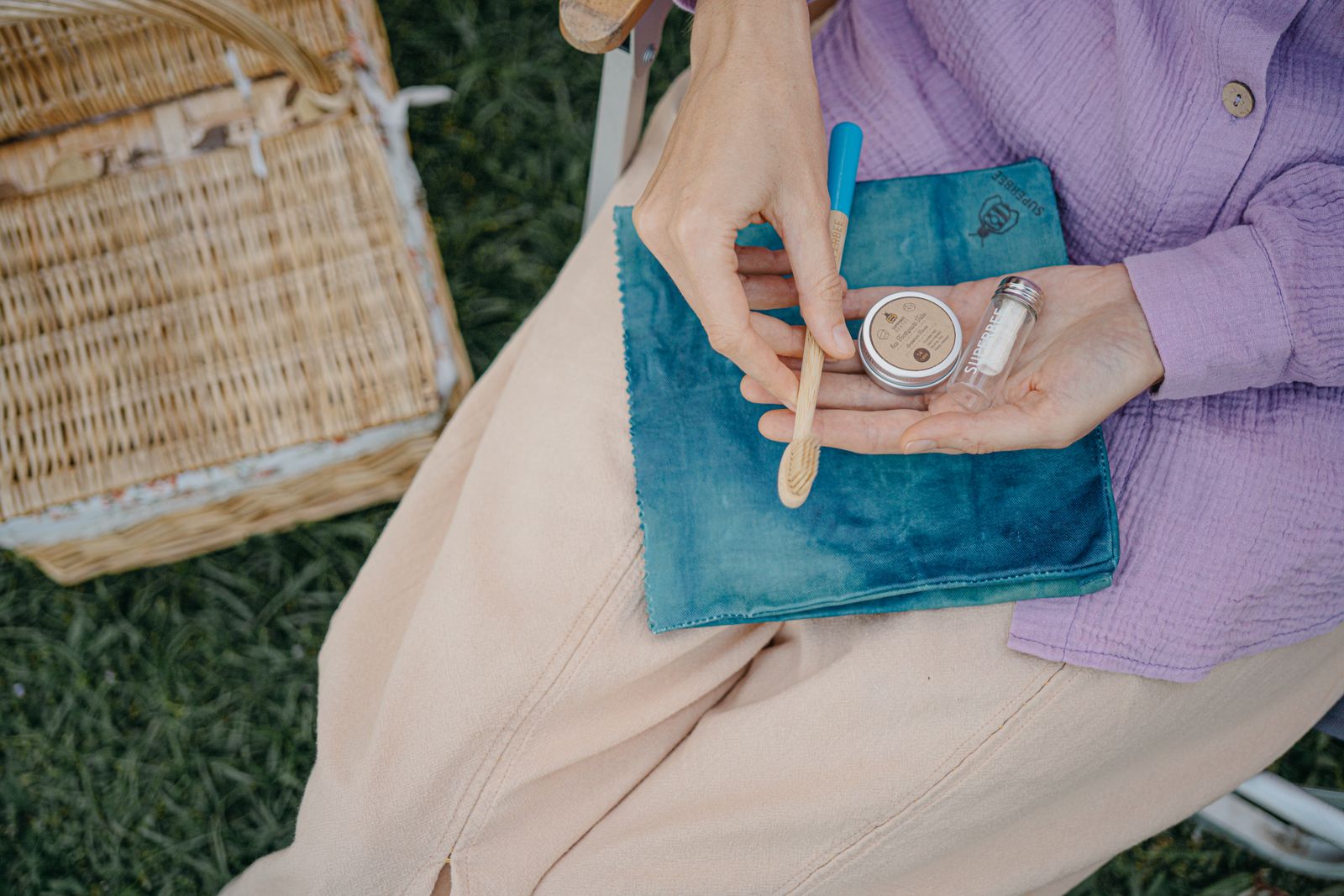Hands opening the Dentos oral care travel kit on a picnic blanket