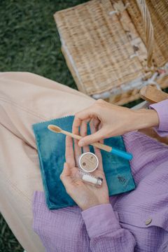 Hands opening the Dentos oral care travel kit on a picnic blanket