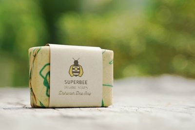 The dishwashing soap bar in its printed beeswax wrap and kraft band on a garden table