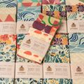 SuperBee Essentials beeswax wraps in assorted prints laid out with their paper sleeves
