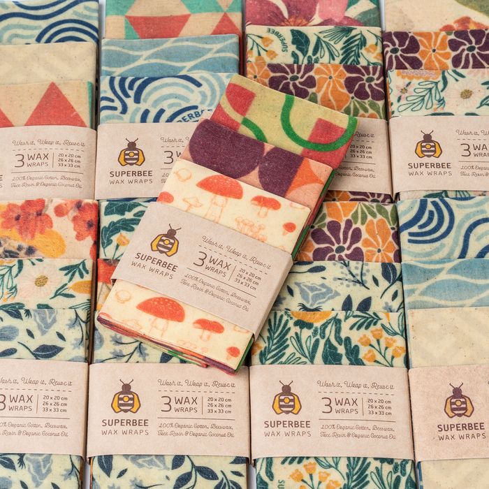 SuperBee Essentials beeswax wraps in assorted prints laid out with their paper sleeves