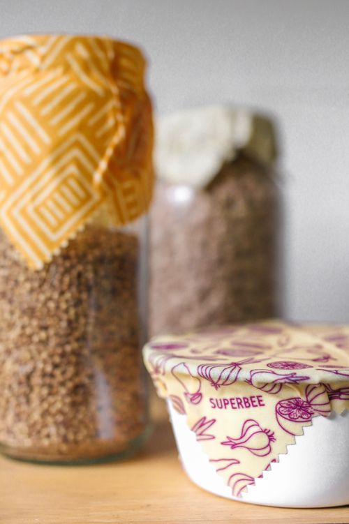 Glass jars of grains and a bowl covered with patterned beeswax wraps