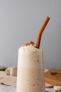 A thick smoothie in a glass with an amber SuperBee glass drinking straw