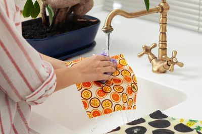 Washing a beeswax cheese wrap in cool water to reuse it