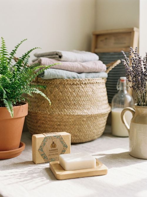 The laundry soap bar and its box beside a basket of folded linen, a fern and lavender