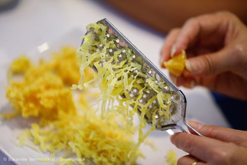 Hands grating a block of beeswax into fine shavings