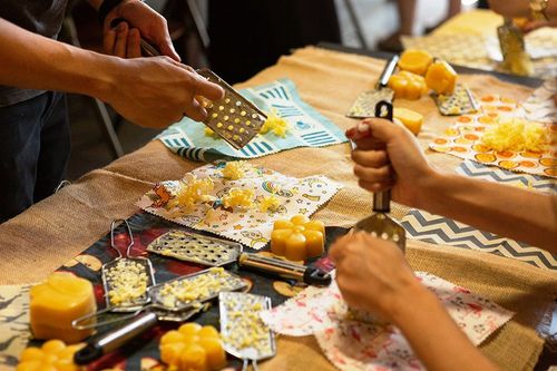 People grating beeswax over fabric at a SuperBee wrap-making workshop