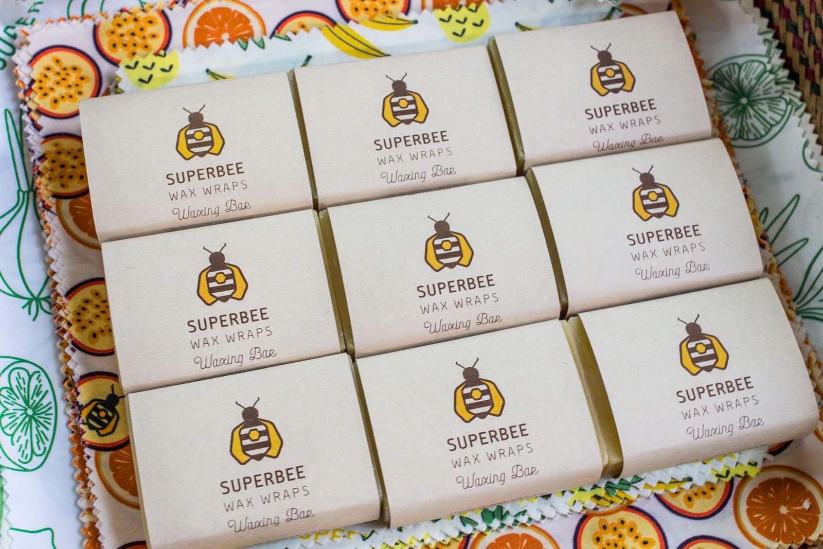 A SuperBee waxing bar held above printed cotton fabric for making your own beeswax wraps