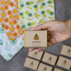 A SuperBee waxing bar held above printed cotton fabric for making your own beeswax wraps