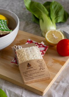 A natural luffa dish scrubber on a wooden board with fresh vegetables