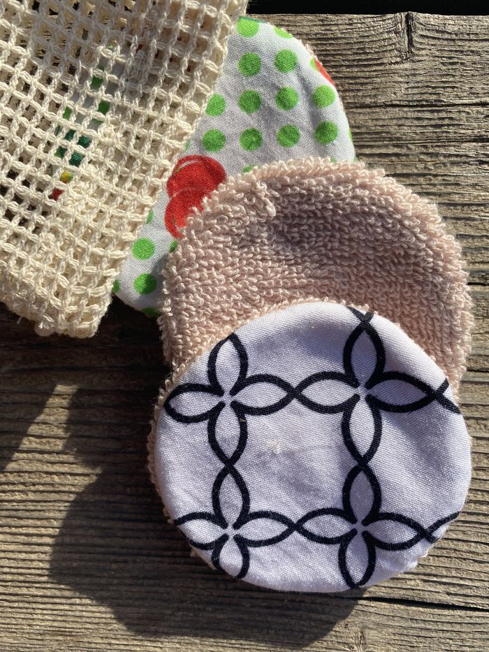 SuperBee reusable organic cotton rounds with their mesh wash bag on weathered wood
