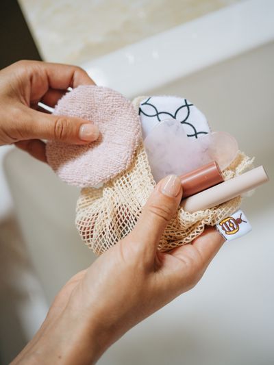Hands taking reusable cotton rounds from their mesh wash bag