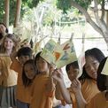 Schoolchildren in yellow shirts holding up beeswax wraps at the workshop