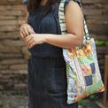A patchwork tote bag sewn from wrap offcuts, carried through the street
