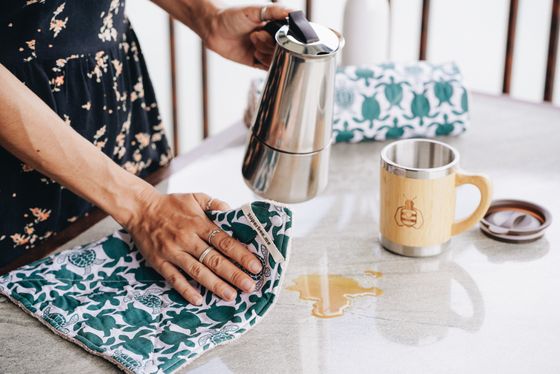 Wiping a spill from a table with a reusable SuperBee kitchen cloth