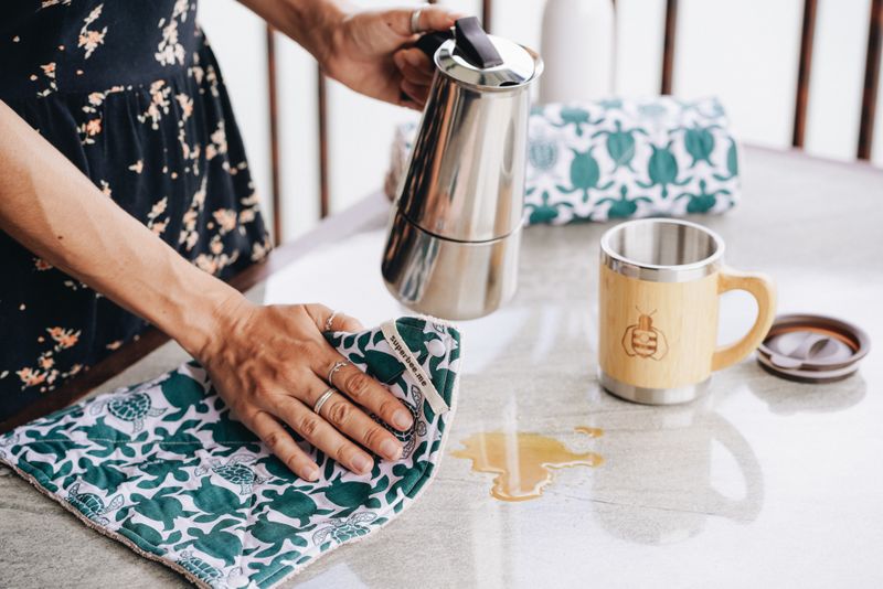 Wiping a spill from a table with a reusable SuperBee kitchen cloth