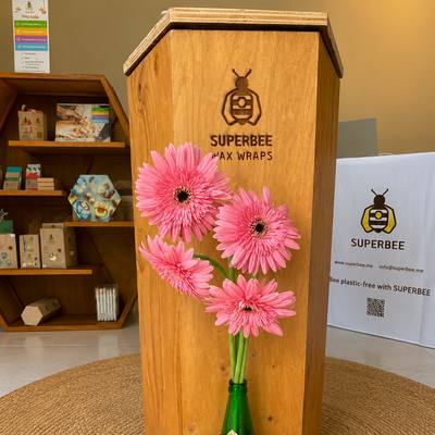 The wooden SuperBee display stand with pink gerberas in a wrapped bottle