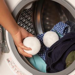 Placing wool dryer balls into a washing machine with laundry